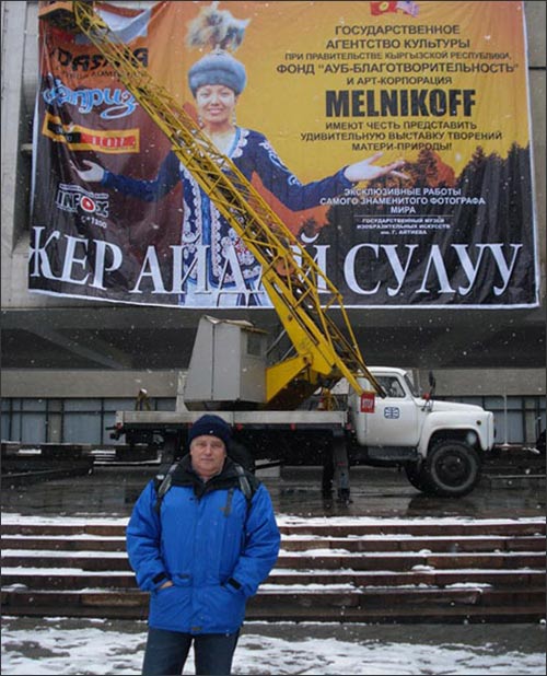 Сергей Мельникофф на фоне афиши своей выставки в Бишкеке